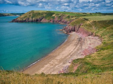 Pembrokeshire, Galler 'deki terk edilmiş Swanlake Sahili' nin kırmızı kumu. Yazın güneşli bir günde, turkuaz bir denizle sahil yolundan alındı..