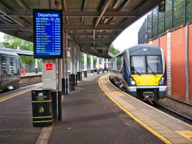 Yerel bir banliyö treni, Belfast, Kuzey İrlanda, İngiltere 'deki Lanyon Place İstasyonu' ndaki boş bir platforma ulaşır. Saat 08.01 'de kalkış saatini gösteren bir ekran var..