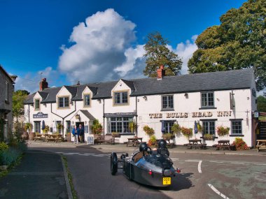 Derbyshire, İngiltere 'de Foolow' da Bulls Head Inn 'in karşısındaki kavşakta gümüş rengi, üç tekerlekli Morgan spor arabaları duruyor. Güneşli bir günde çekildi Sonbaharda mavi gökyüzü.