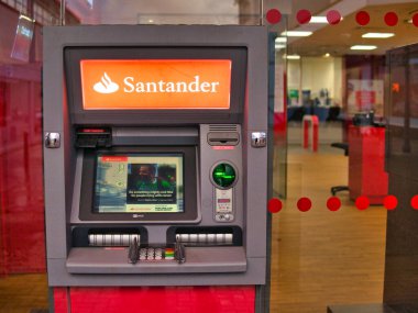 Santander 'in İngiltere' deki bir şubesinin önünde otomatik bir veznedar (ATM). Bankanın içi arka planda görünür..