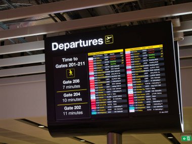 Manchester, İngiltere - 21 Ocak 2024: İngiltere 'deki Manchester Havalimanı' nda elektronik uçuş bilgi ekranı. Uçuş zamanları ve yürüme zamanları çeşitli kapılara gösterilir.