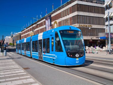 Stockholm, Sweden - Jun 25 2024: A blue tram on the Stockholm tramway network, which forms part of the public transport system in Stockholm, the capital city of Sweden. Taken on a sunny day in summer. clipart