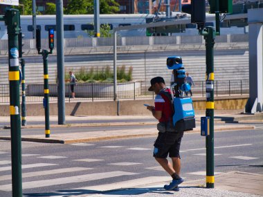 Stockholm, İsveç - 26 Haziran 2024: Google Maps markalı sırt çantası kamera teknolojili bir yaya Stockholm, İsveç 'te yürürken elde tutulan bir cihaza danışıyor.