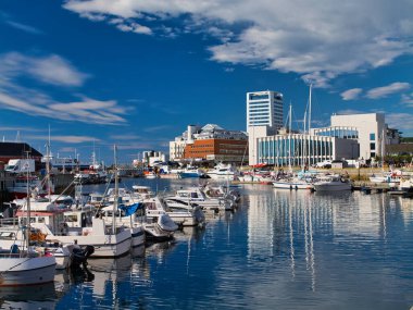 Bodo, Norveç - 17 Haziran 2024: Norveç kıyısındaki Bodo 'ya demir atmış tekneler. Yazın güneşli bir günde mavi bir gökyüzü ve ışık bulutuyla çekildi..