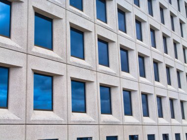 Kopenhag, Danimarka - 10 Haziran 2024: A.P. 'nin şirket ofislerinin modern beton ve cam mimarisi Moller - Maersk, Kopenhag, Danimarka. Pencerelere yansıyan bulutlu mavi bir gökyüzü.