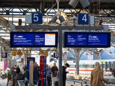 Cologne, Germany - Jun 9 2024: Train information signs above a busy platform at Cologne - Koln Station - Hauptbahnhof. clipart