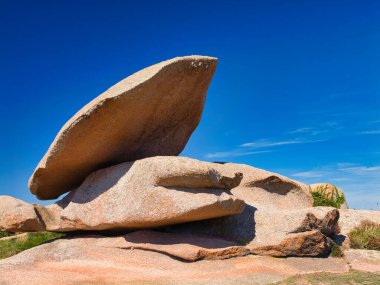 Perros-Guirec, Lannion, İngiltere 'nin Ploumanac' h yakınlarındaki ünlü Pembe Granit Sahili 'nde kaya oluşumları. Yazın güneşli bir günde çekildi, mavi gökyüzü ve ışık bulutu ile.