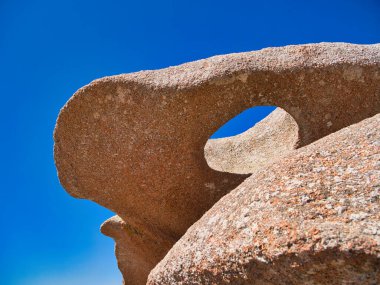 Rock formations on the famous Pink Granite Coast near Ploumanac'h in Perros-Guirec, Lannion, Brittany in Northern France. Taken on a sunny day in summer, with a blue sky and light cloud. clipart