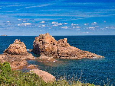 Perros-Guirec, Lannion, İngiltere 'nin Ploumanac' h yakınlarındaki ünlü Pembe Granit Sahili 'nde kaya oluşumları. Yazın güneşli bir günde çekildi, mavi gökyüzü ve ışık bulutu ile.