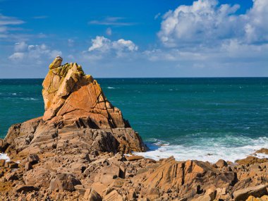 Kuzey Fransa 'da Le Diben ve Plougasnou çevresindeki engebeli Britanya kıyıları. Yazın sonlarında güneşli bir günde mavi gökyüzü ve sahil yolundan gelen ışık bulutlarıyla çekildi..