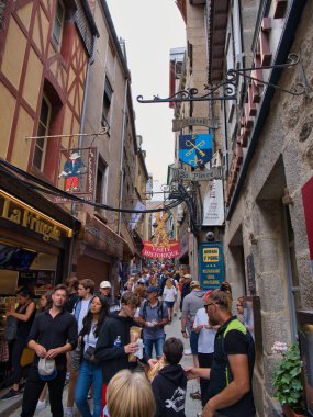 Normandiya, Fransa - 4 Eylül 2024: Turistler Mont-Saint-Michel adasının dar sokaklarını dolduruyorlar. Fransa 'nın Normandiya' nın kuzey batı kıyısında bir Dünya Mirası Alanı.