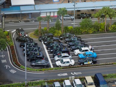 Japonya 'nın başkenti Kagoshima' da kuyruğa giren taksilerin hava görüntüsü. Görüntü siyah, beyaz ve mavi taksilerin bir istasyon yakınında düzenli bir şekilde dizilmiş bir karışımını yakalıyor..