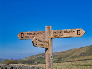 İngiltere, Yorkshire Dales yakınlarındaki Pennine Bridleway tabelasında, manzaralı kırsal ve ulusal park manzaraları boyunca yürüyüş ve bisiklet rotaları işaretlenmektedir..