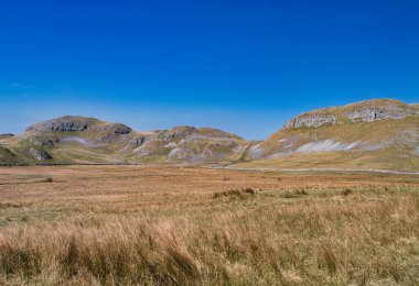 Kireçtaşı tepeler ve kuru taş duvarlar Attermire Scar, Settle 'da derin mavi bir gökyüzünün altında Yorkshire Dales Ulusal Parkı' nda, İngiltere 'nin klasik bir dağ manzarası.