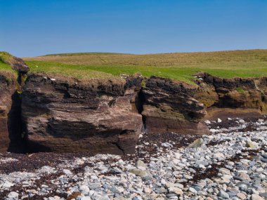 Heoga Ness, Shetland 'da kayalık bir plajın tepesinde turba katmanları, engebeli sahil cazibesini gösterir..