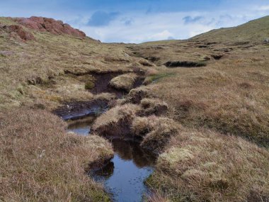 Muckle Roe 'nun uzak sulak arazisinde yumuşak yamaçlar ve engin gökyüzünün altında sakin bir atmosfer..