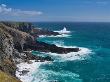 Engebeli kayalıklar, parlak mavi Atlantik Okyanusu 'yla İrlanda' nın Mizen Tepesi 'nde, açık bir gökyüzünün altında buluşuyor..