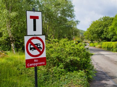 Sneem, İrlanda - Haziran 05 2025: İrlanda 'nın Sneem kentinde ağaçlarla kaplı bir yol kenarında kamp kurmayı yasaklayan bir yol tabelası bulunuyor.