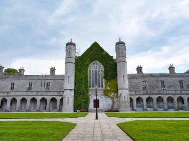 Galway, İrlanda - 13 Haziran 2025: Galway, İrlanda 'daki Majestic üniversite binası, sarmaşık dinamik bir gökyüzü altında taş cephesine tırmanıyor.