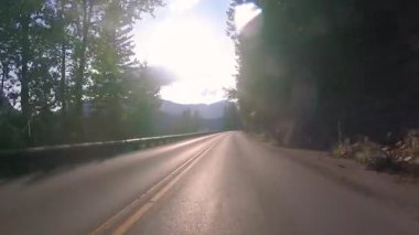 Yaz mevsiminde Montana, ABD 'deki Buzul Ulusal Parkı' nda güneşe Giden Yol 'da kör edici güneşe doğru sürerken,