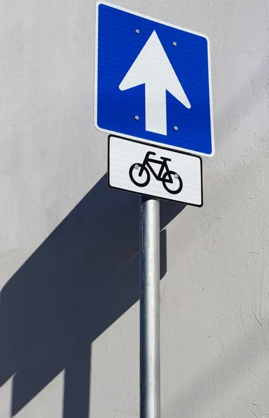 One way and bicycle road sign in front of a wall