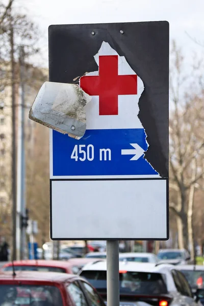 Torn hospital traffic sign on the road side
