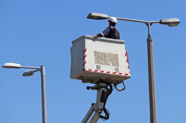 Elektrik işçisi sokak lambasının yanında çalışıyor.