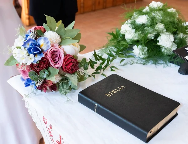 Bible book on the table next two bouquet of flowers at a wedding