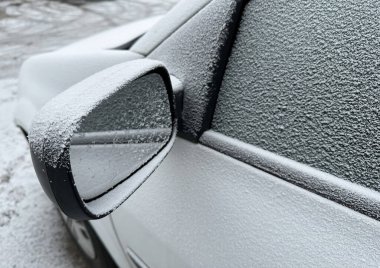 Kış zamanı karla kaplı bir arabanın yan aynası.