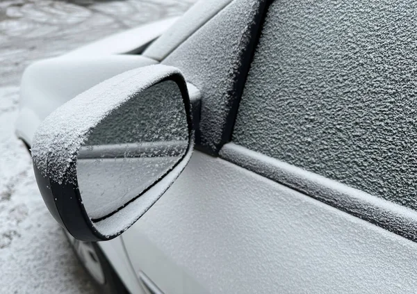 Kış zamanı karla kaplı bir arabanın yan aynası.