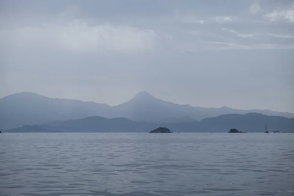 stock image sea and mountains silhouette view in cloudy mist day, Blue Sea and shade of mountain, empty peaceful nordic landscape