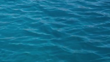 Açık mavi deniz suyu güneşli bir günde yavaşça el sallıyor. güzel turkuaz su yüzeyi