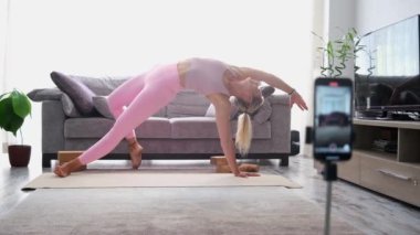 woman practicing yoga poses stretching in front of phone camera sport blogger teacher yoga online class wellness coach