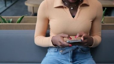 Afro-Amerikalı kadın, yazı yazarak çalışıyor. Akıllı telefon konuşmaları yapıyor. Kafe öğrencisinde oturuyor, serbest çalışan bir iş kadını.