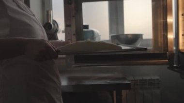 Kadın elleri ekmek hamurunu fırına veriyor, ev yapımı mayalı somun ekmeği pişiriyor. Pastane. 