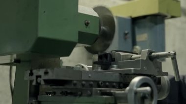 Fabrikada elektrikli testere kullanan bir adam. Dairesel testere metal parçaları üretim makinesinde dönüyor. 