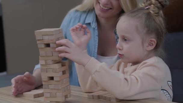 幸せな家族の母親と娘の肖像自宅で低テーブルでボードゲームをプレイし タワー笑顔週末の活動から木製のブロックを引っ張っ — ストック動画