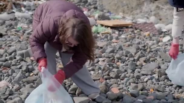 随着志愿者们在海滩上收集塑料碎片并将其放进垃圾袋 减少塑料污染和环境问题的理念正在付诸实施 — 图库视频影像