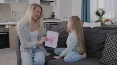 Mutlu kadınlar günü, küçük kız annesini 8 Mart 'ta tebrik eder ve ona boyalı kalple tebrik kartı verir. Hem güler hem de aile tatilini birlikte geçirir.