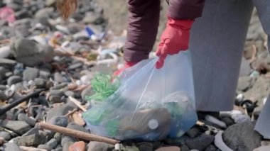 Plajdaki plastik atıkları temizleyen, sürdürülebilirliği ve korunmayı destekleyen bir kadın. Çöp geri dönüşümü ve çevresel bakım kavramı