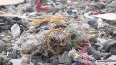 Plaj plastik atıklarla ve çöplüklerle dolu. Çevre kirliliğinin yıkıcı etkilerini vurguluyor..