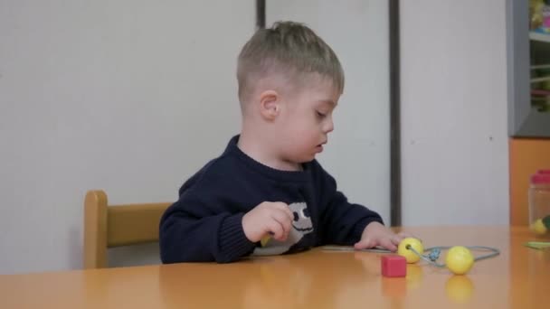 幾何学的な形のおもちゃで遊んでダウン症候群と一緒に暮らすかわいい子供 教育用ブロックを備えた学習ゲームです — ストック動画