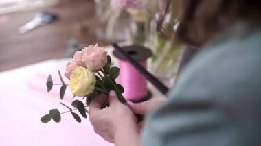 Yetenekli kadın çiçekçi dükkanı sahibi müşterilerine neşe ve mutluluk getiren pembe ve sarı güllerden oluşan nefes kesici bir düzenleme yapıyor..