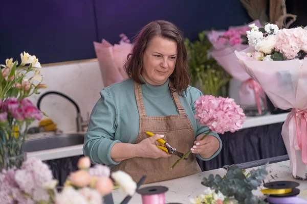 inside the charming flower shop, the creative female business owner expertly arranges a stunning bouquet preparing for work day