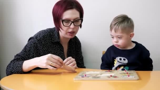 幸せなお母さんと小さな男の子はダウン症候群と一緒に住んでいるおもちゃで教育ゲームをプレイAtkidsセンター — ストック動画