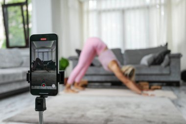 woman practicing yoga poses stretching in front of phone camera sport blogger teacher yoga online class wellness coach