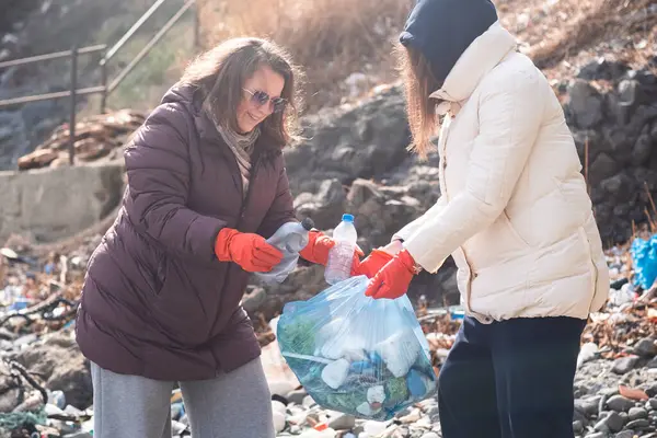 stock image An environmentally aware volunteers taking action against the ocean plastic problem. Collect waste and other garbage from the beach side and packing to bags for recycling. 