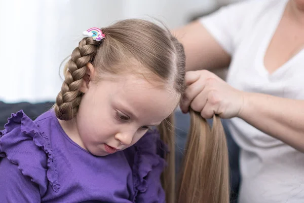 Stock image hairdresser stylist brushing child girl blond hair and styling hairdo braid hairstyle getting ready for scool or going out