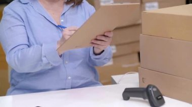 Lojistik sevkiyat çevrimiçi siparişleri. Küçük işletme sahibi, e-ticaret ofisinde teslim edilecek şeyleri paketliyor. Barkodları tarıyor ve takip ediyor.