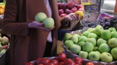 İp torbası taşıyan genç bir kadın marketteki meyve sebze rafından meyve seçiyor sağlıklı gıda gıdası.